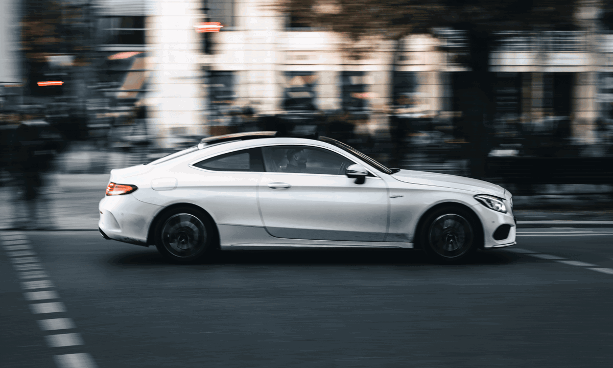 Mercedes white driving on street