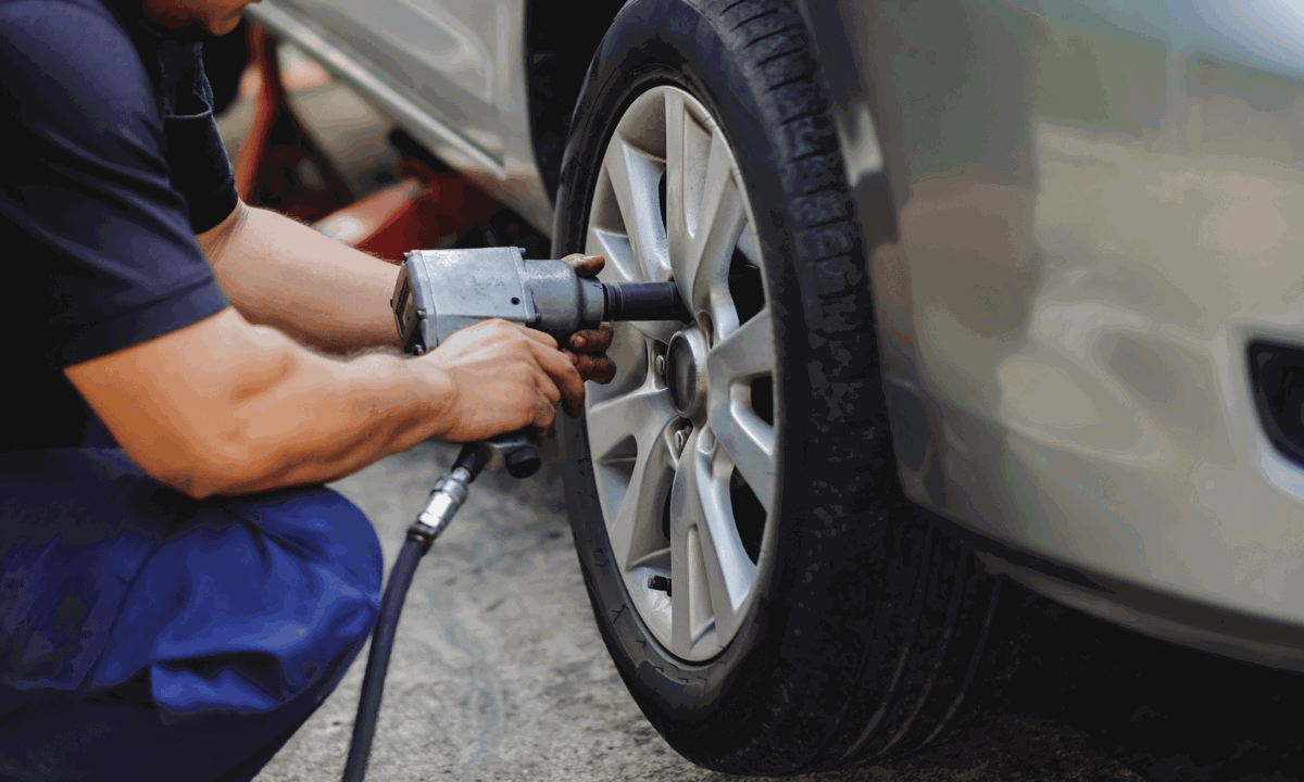 An alloy wheel being removed by a technician.