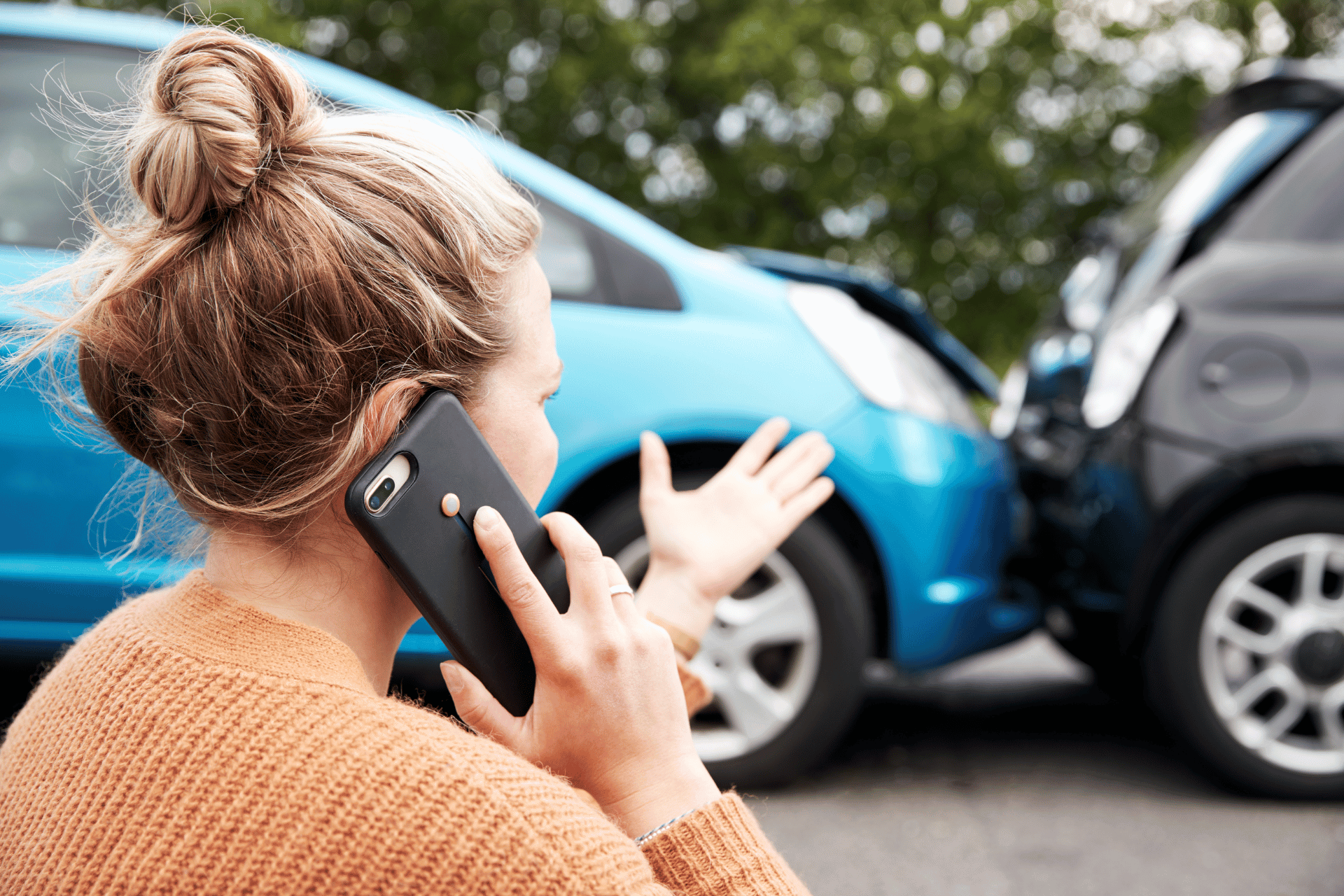 Lady on the phone in front of crashed cars.